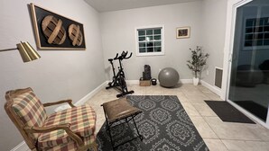 A home gym with exercise equipment, a chair, a rug, and a potted plant. - Modern & Convenient 3/2 Home (Lake City)
