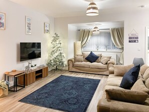 Una sala de estar con televisor, árbol de Navidad, sofá y alfombra.