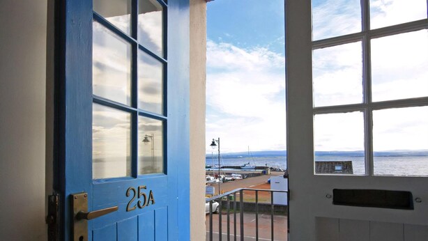 A blue door with the number 25A, leading to a balcony with a view of the sea and boats. - 3 bedroom accommodation in Avoch, near Fortrose (Avoch, near Fortrose)