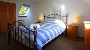 A bedroom with a bed, two bedside tables with lamps, a wooden wardrobe, a window with a view, and a ceiling light fixture. - 3 bedroom accommodation in Avoch, near Fortrose (Avoch, near Fortrose)