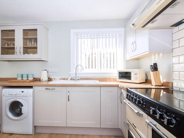 Une cuisine compacte équipée d’un lave-linge, d’un four à micro-ondes et d’une cuisinière.