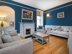 A living room with a fireplace, a sofa, a coffee table, and a painting on the wall.