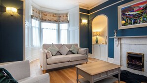 Een woonkamer met een bank, een salontafel, een open haard en een schilderij aan de muur.