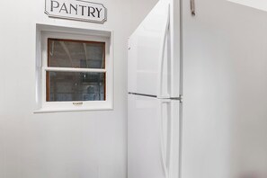 A white pantry with a window and a white refrigerator. - Place on Pecan | Close to Main in Cowboy Capital (Bandera)