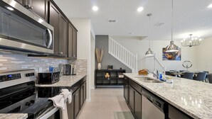 Una cocina moderna con armarios oscuros, electrodomésticos de acero inoxidable y encimera de granito.