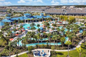 A resort with multiple swimming pools, palm trees, and a large building with blue roofs. - Disney Area 5BR Home with Heated Pool ,Resort Amenities at Windsor Island Resort (Davenport)