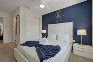 A bedroom with a large bed, a nightstand with a lamp, a ceiling fan, and a decorative wall piece. - Disney Area 5BR Home with Heated Pool ,Resort Amenities at Windsor Island Resort (Davenport)
