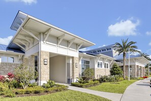 A modern two-story house with a covered porch, stone facade, and a well-maintained garden with various plants and a palm tree. - Disney Area 5BR Home with Heated Pool ,Resort Amenities at Windsor Island Resort (Davenport)