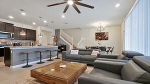 Una sala de estar moderna con sofá, mesa de centro y área de cocina con taburetes de bar.
