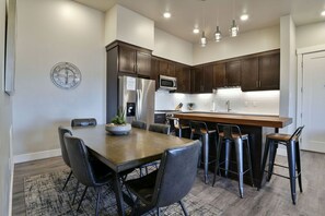 A modern kitchen with dark wood cabinets, stainless steel appliances, and a central island with bar stools.