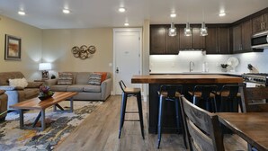 A modern kitchen with dark wooden cabinets, a central island with stools, and pendant lighting. - Sage Creek Desert Escape C2 - Luxury Pool & HotTub (Moab)