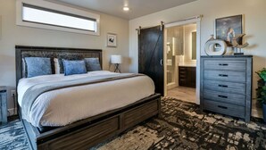 Quarto com cama grande, ventoinha no teto, cômoda e porta deslizante que dá para um banheiro.