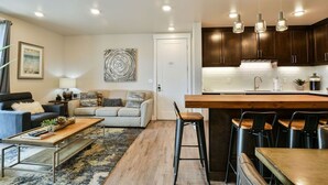 A modern kitchen with dark wood cabinets, a central island with bar stools, and pendant lighting. - Moab Arches C4 "Sage Creek" - Heated Pool-Hot Tubs (Moab)