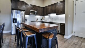A modern kitchen with dark wood cabinets, stainless steel appliances, and a central island with bar stools. - SageCreek C5 - Best Pool & Red Rock View - Hot Tub (Moab)