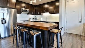 A modern kitchen with dark wood cabinets, stainless steel appliances, and a central island with bar stools. - Sage Creek Resort Moab - ArchView Escape C7 (Moab)