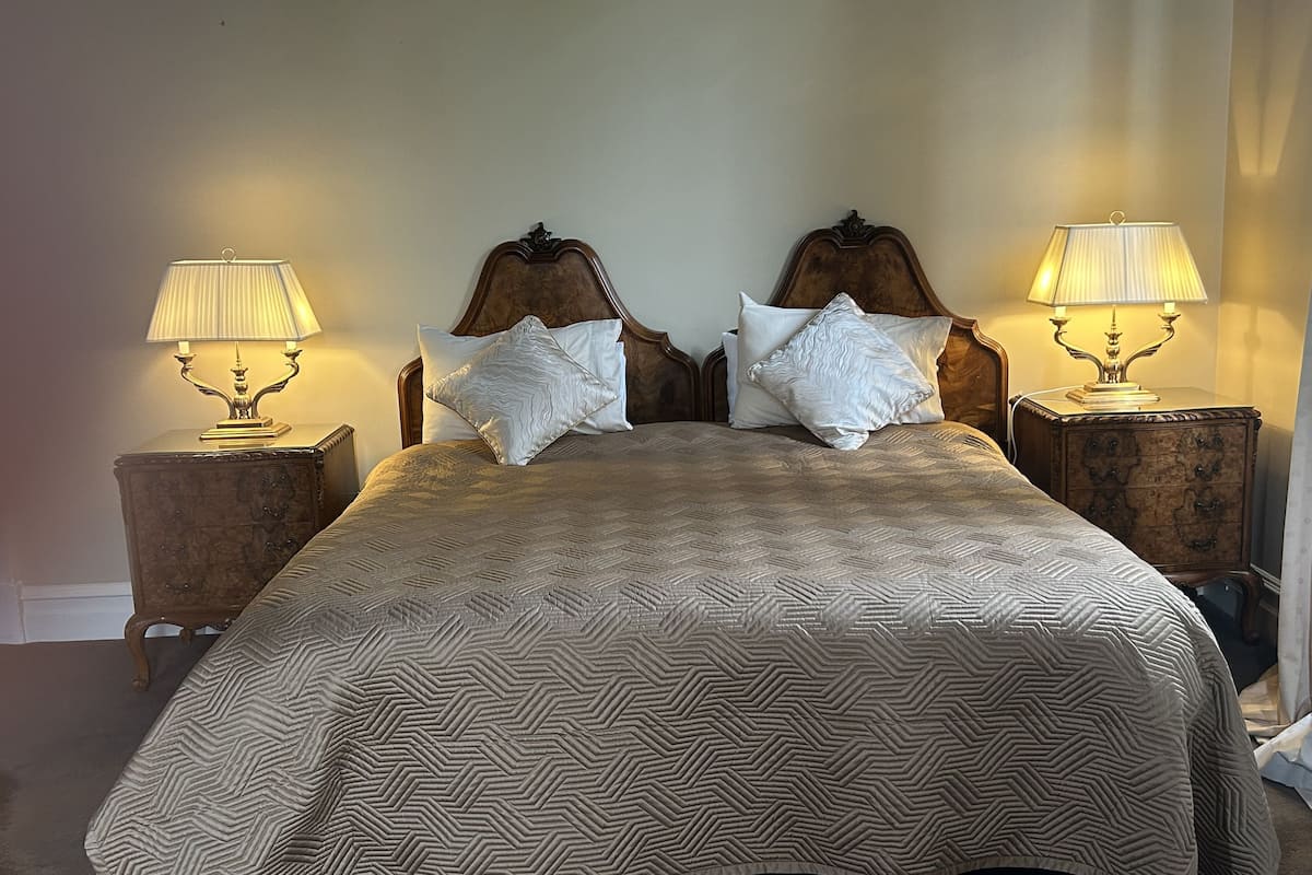 A bed with a patterned bedspread, two nightstands with lamps, and a wooden headboard.