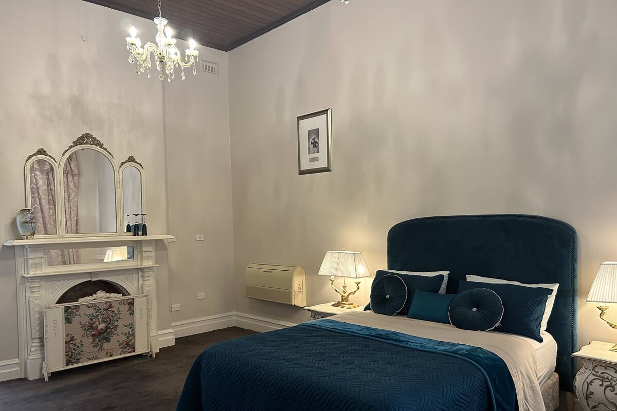 A bedroom with a large bed, a fireplace, and a chandelier.