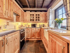 Een keuken met houten kastjes, een fornuis en een spoelbak.