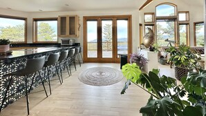 Eine geräumige Küche mit Bar, großen Fenstern und Blick ins Freie.