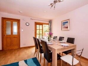 A dining room with a wooden table, chairs, and a window with curtains.