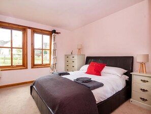 A bedroom with a bed, a nightstand, a dresser, and a window.