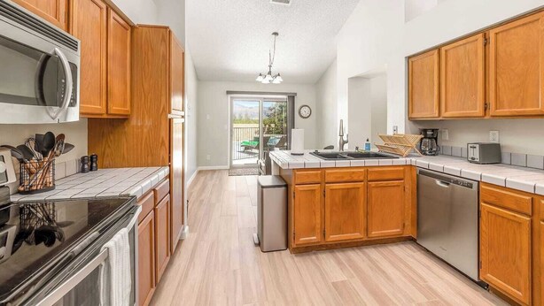 A modern kitchen with wooden cabinets, a microwave, a dishwasher, and a large island with a sink.