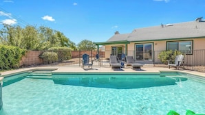 A clear swimming pool with lounge chairs and a covered patio area.