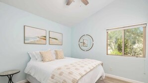 A bedroom with a bed, a round mirror, and two framed pictures on the wall.