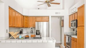 A modern kitchen with wooden cabinets, stainless steel appliances, and a central island with stools.