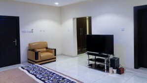 Uma sala de estar moderna com um sofá de couro, uma TV de tela plana em um móvel, um guarda-roupa e uma porta.
