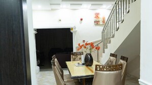 Uma sala de jantar com mesa, cadeiras e um vaso de flores.
