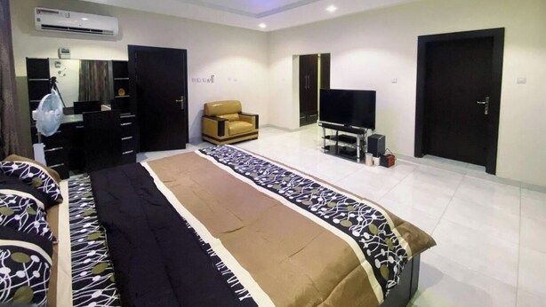 Quarto moderno com uma cama grande, uma TV e um sofá.