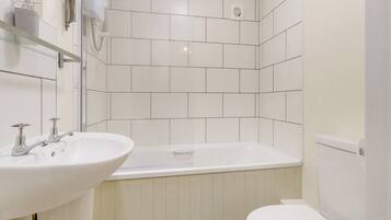 Un baño moderno con lavamanos blanco, bañera y retrete.