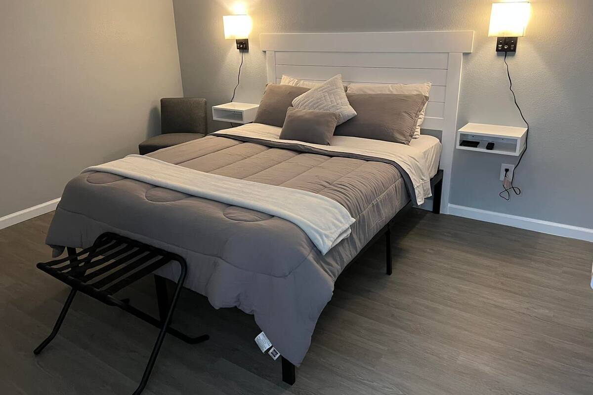 A neatly made bed with a headboard, two bedside tables, and a bench at the foot of the bed.