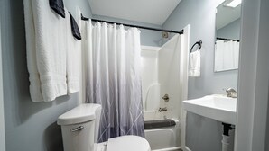 A bathroom with a toilet, shower, bathtub, and sink. - The Crossroad Inn (Lineville)