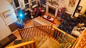 A spacious living room with a fireplace, a staircase, and a Christmas tree. - RVH"S/
 Rm B  in a Home/Shared Living Space  (Surrey)