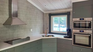 A modern kitchen with grey cabinets, a stainless steel range hood, a window with a view, and built-in ovens. - Gorgeous home in Fjälkinge with kitchen (Fjälkinge)