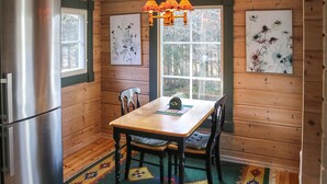 A wooden cabin interior with a dining table, chairs, a refrigerator, and artwork on the walls. - Gorgeous home in Fjälkinge with kitchen (Fjälkinge)