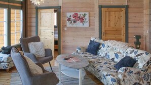 A cozy room with a sofa, armchair, and a small table. There is a painting on the wall and a door with a window. - Gorgeous home in Fjälkinge with kitchen (Fjälkinge)