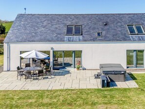 A modern house with a patio, outdoor seating, and a hot tub. - The Longhouse at Threave (Castle Douglas)