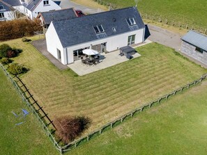 A residential property with a large lawn, a patio with outdoor furniture, and a fenced yard. - The Longhouse at Threave (Castle Douglas)