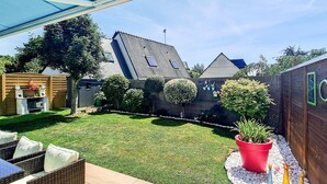 Un patio trasero con césped, valla de madera, zona de barbacoa y mobiliario exterior.