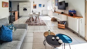 Una sala de estar moderna con un sofá, una mesa de centro, un televisor y un comedor con una mesa y sillas.