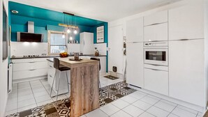 Una cocina moderna con armarios blancos, una pared de acento color turquesa, una isla de madera y una alfombra estampada.