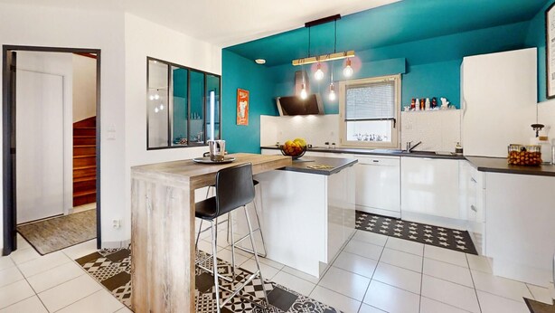 Una cocina moderna con una pared de acento color aguamarina, una barra y un comedor.