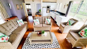 A living room with a sofa, two armchairs, a coffee table, and a patterned rug. - Natura Turtle Bungalow (Rarotonga)