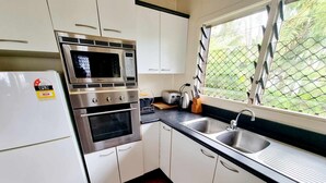 A compact kitchen with a refrigerator, microwave, oven, and sink. - Natura Turtle Bungalow (Rarotonga)