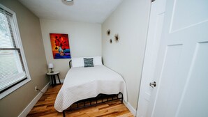 Ein Schlafzimmer mit einem Bett, einem Nachttisch, einer Lampe und einem Gemälde an der Wand.