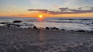 A beach with a sunset, rocky shoreline, and waves. - Afforable & quaint upstairs 2Bedroom 1Bath apartment with lanai and Ocean views (Kailua-Kona)