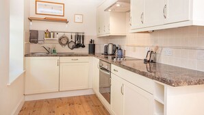 A kitchen with white cabinets, a granite countertop, and wooden flooring. - 2 bedroom accommodation in Fortrose (Fortrose)